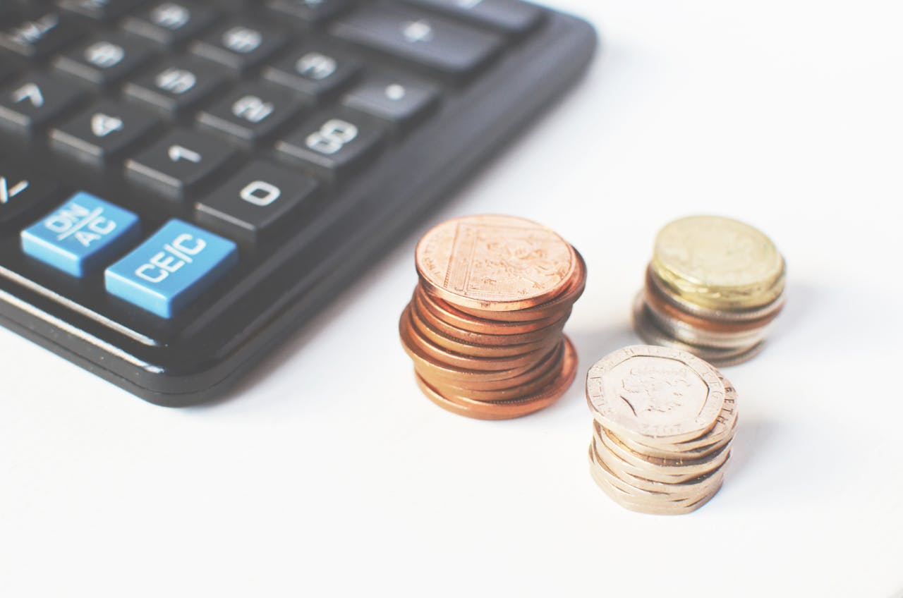 testimonials-img Close-up of stacked coins and a calculator symbolizing financial strategy and budgeting.