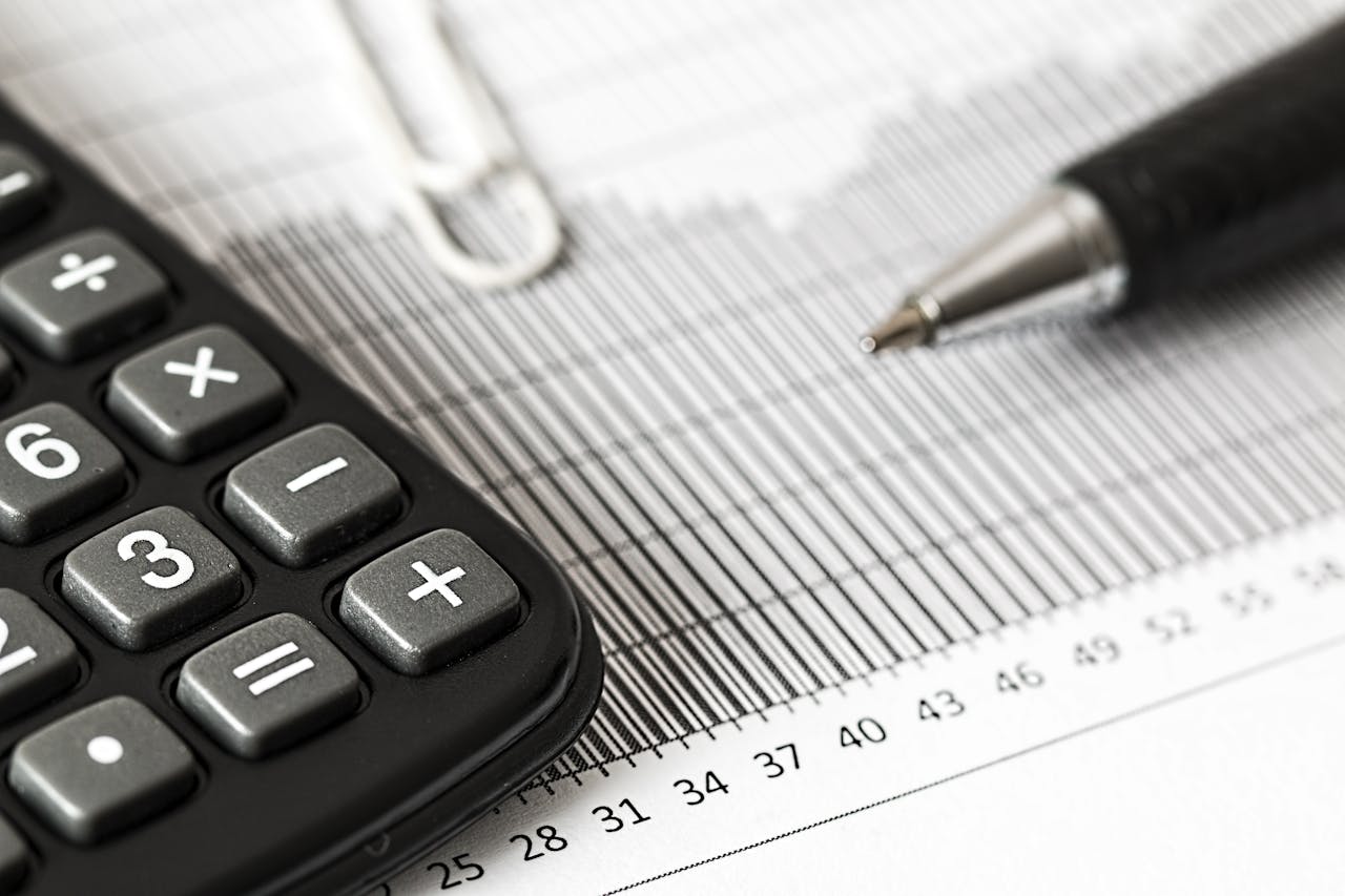 about-01 Close-up of a calculator and pen on a bar graph, representing finance and accounting.